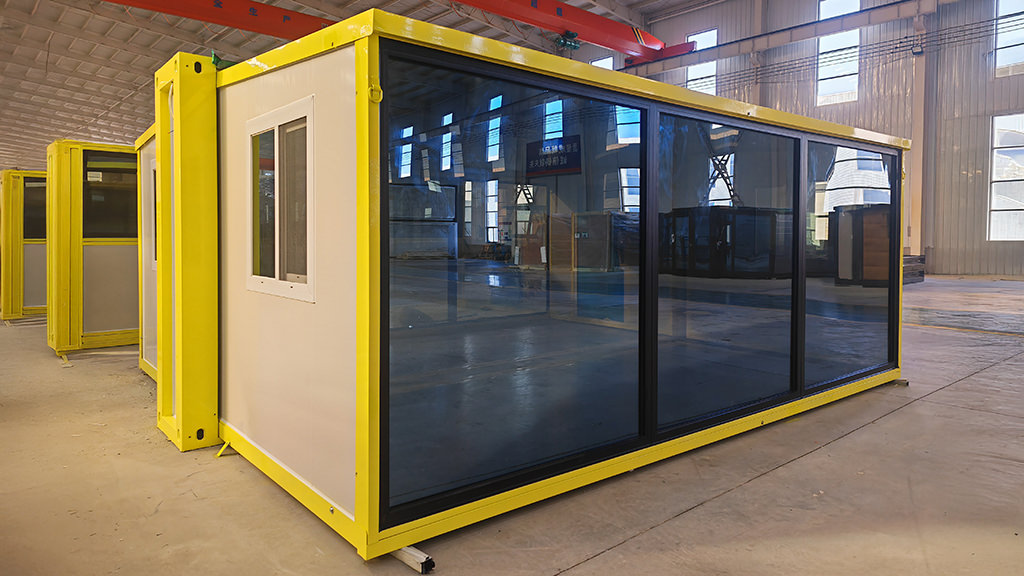 Expandable container home featuring full-width glass sliding doors in factory setting